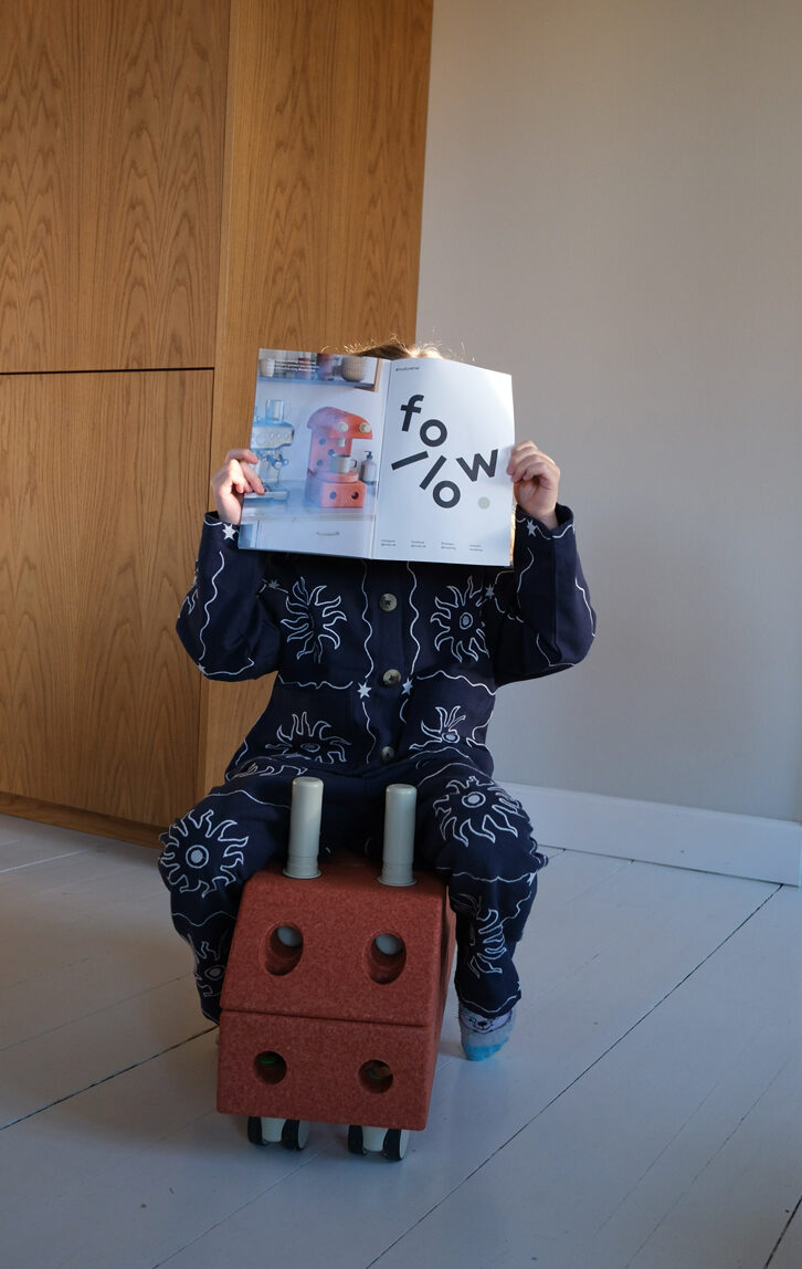 Pige sidder med et magasin foran hovedet på en bil lavet i modu