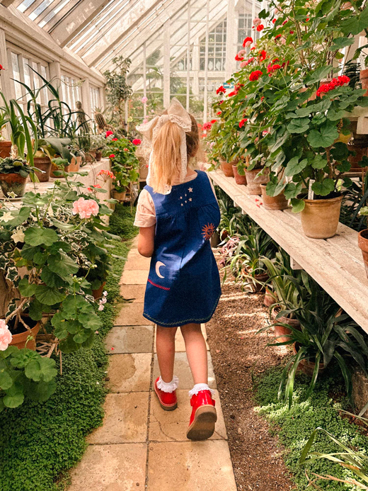 Pige går i et drivhus med Sissel Mini tøj på